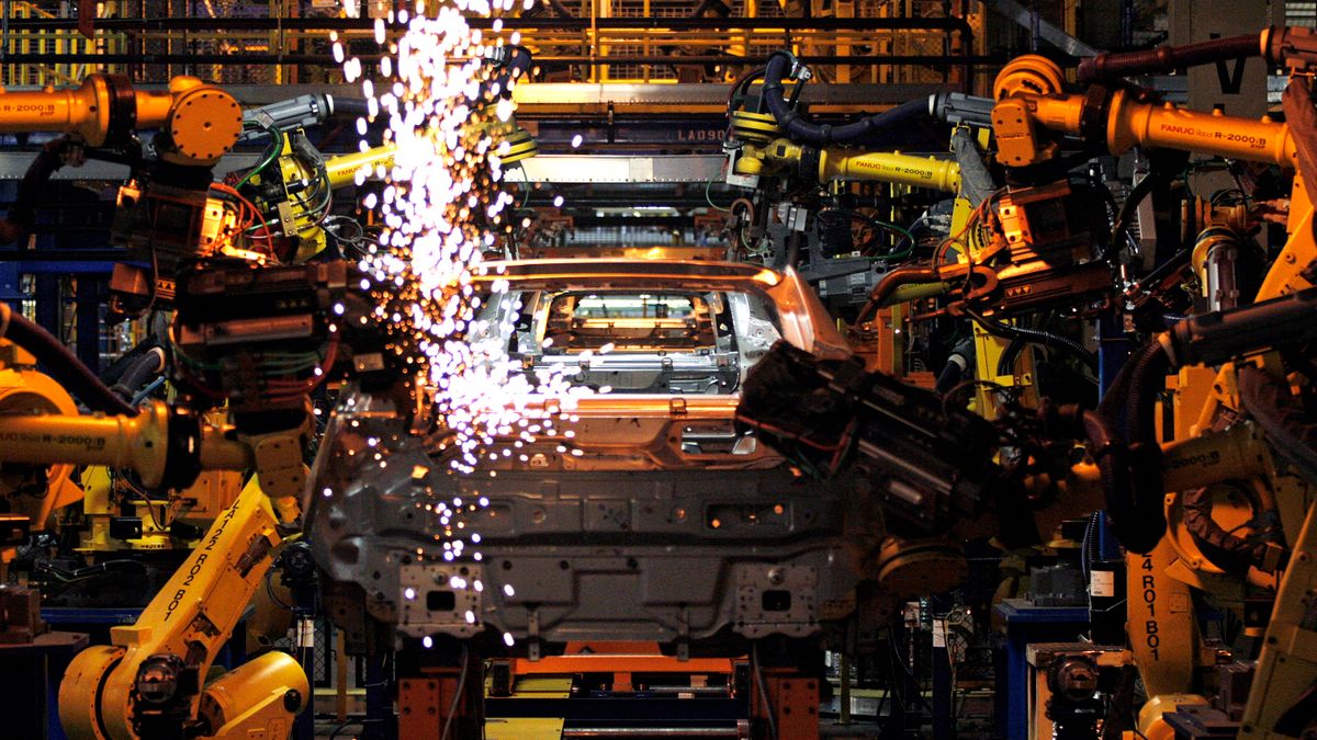 A Chevy Volt goes through an assembly line as sparks fly and robotic arms work to build it.