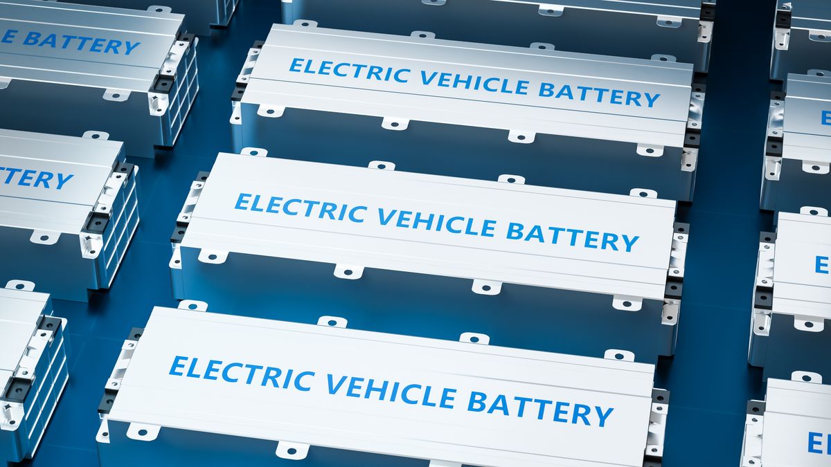 An EV lithium-ion battery module inside a white metal enclosure laying on a dark blue-gray ground.