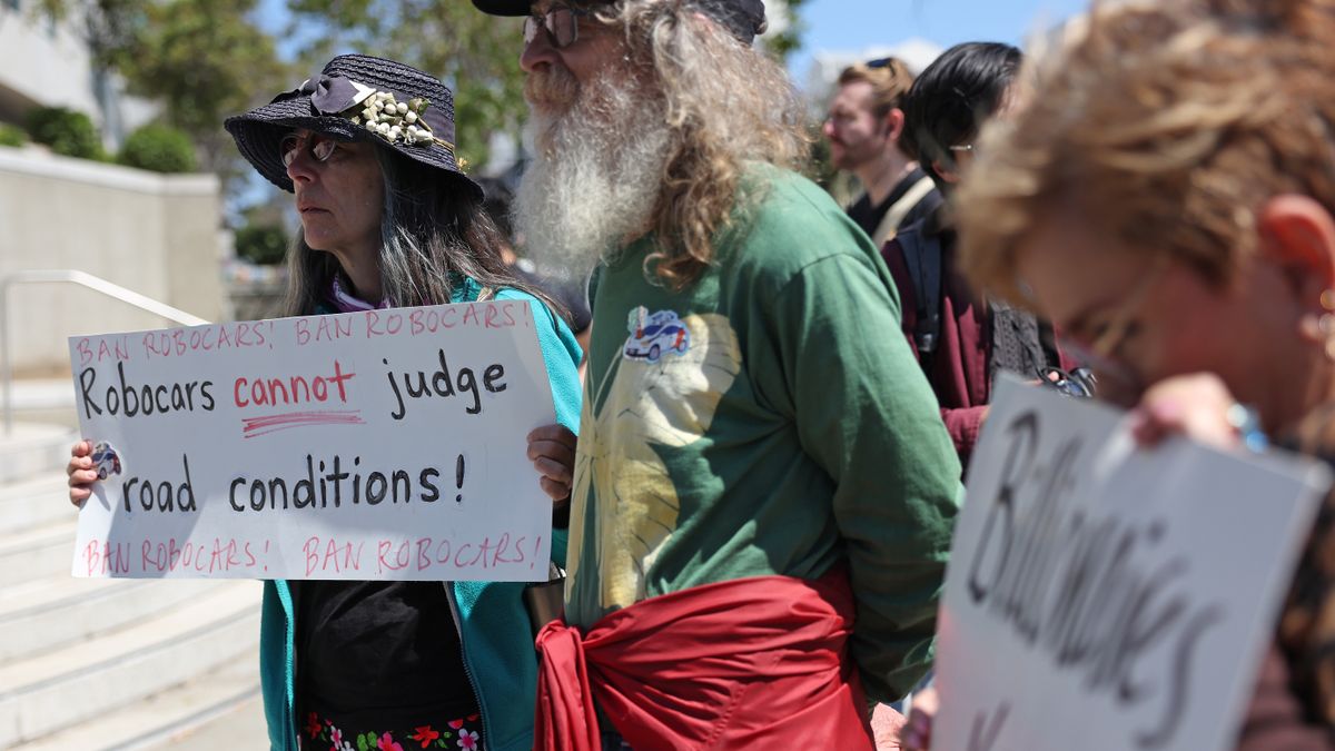 A protester holds a sign during a demonstration opposing self-driving robotaxis.