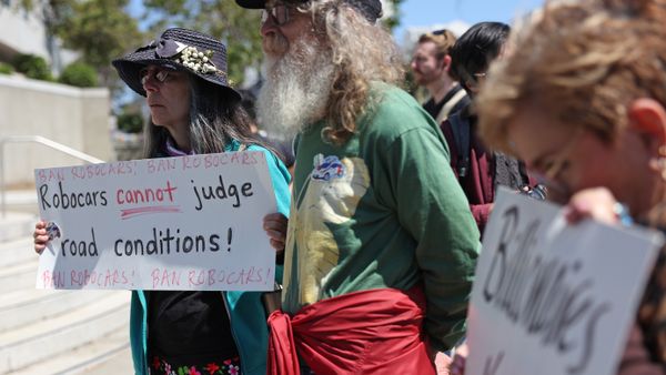 A protester holds a sign during a demonstration opposing self-driving robotaxis.