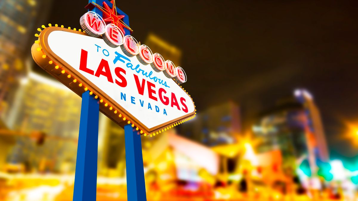 Nighttime photo of the "Welcome to Las Vegas" sign with blurred hotels and lights in the background.