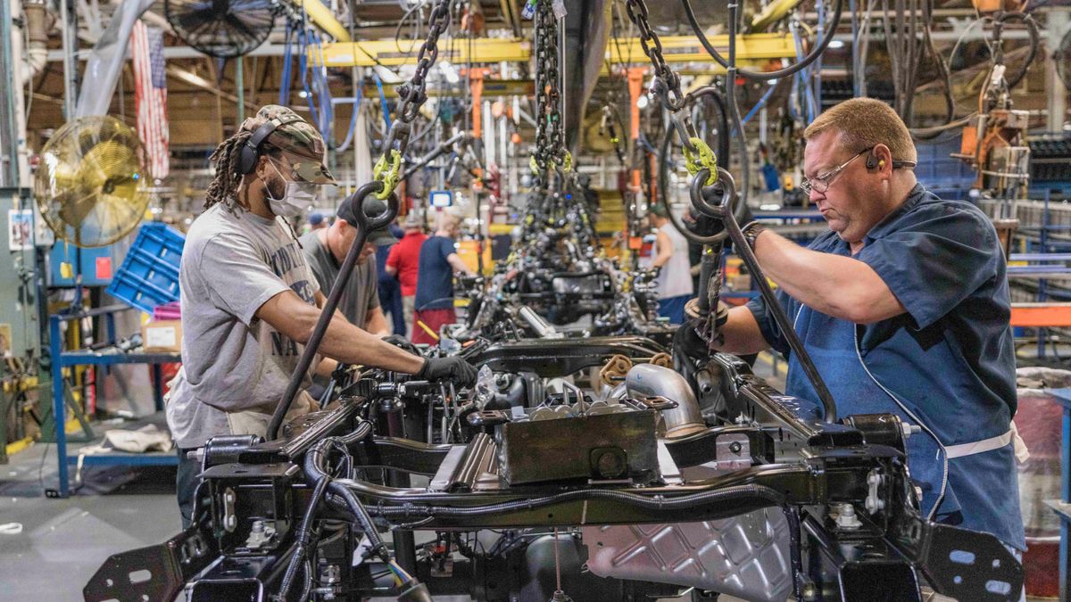 Two employees at Ford's Kentucky Truck Plant work on a frame of a F-Series Super Duty pickup.
