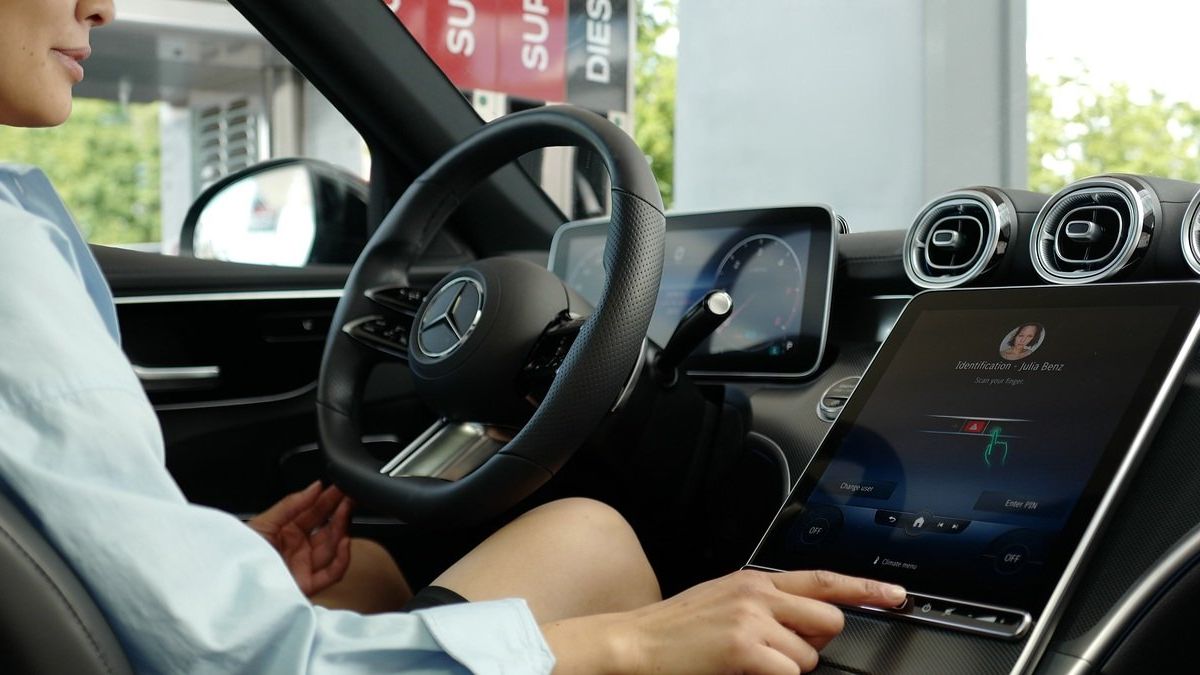 A driver presses buttons on a Mercedes-Benz infotainment system to make a purchase using her fingerprint.