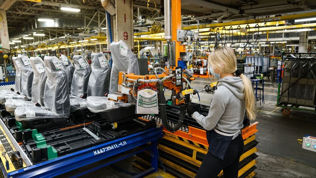 A female worker at General Motor's Oshawa plant in Canada works on an assembly line with car seats lined up in front of her.