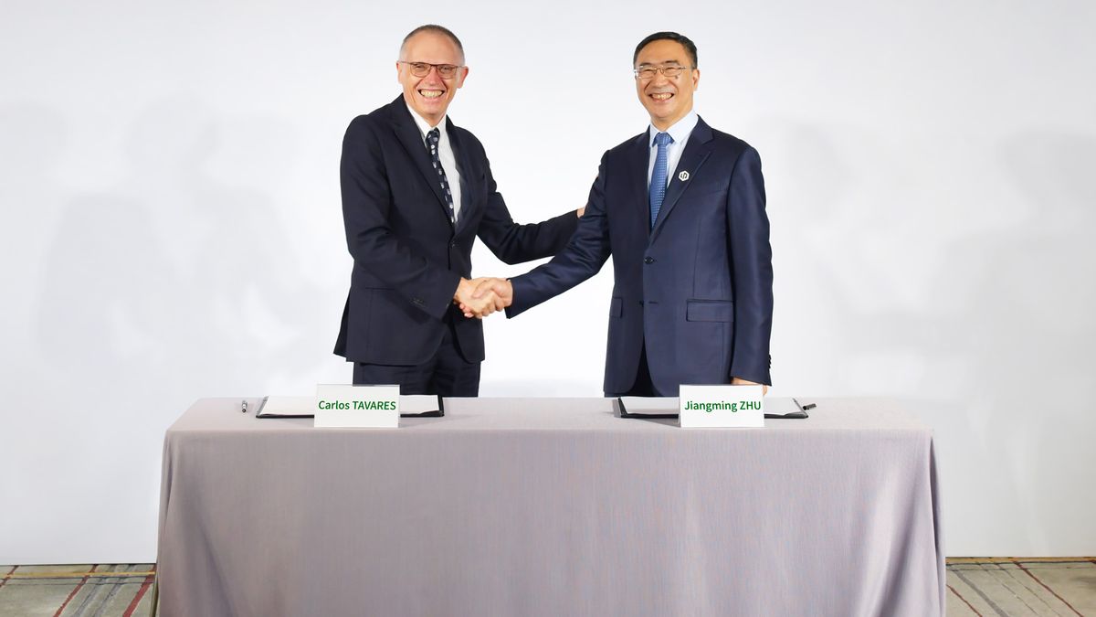 Stellantis CEO Carlos Tavares shakes hands with Leapmotor CEO Zhu Jiangming behind a table at a strategic cooperation signing ceremony.